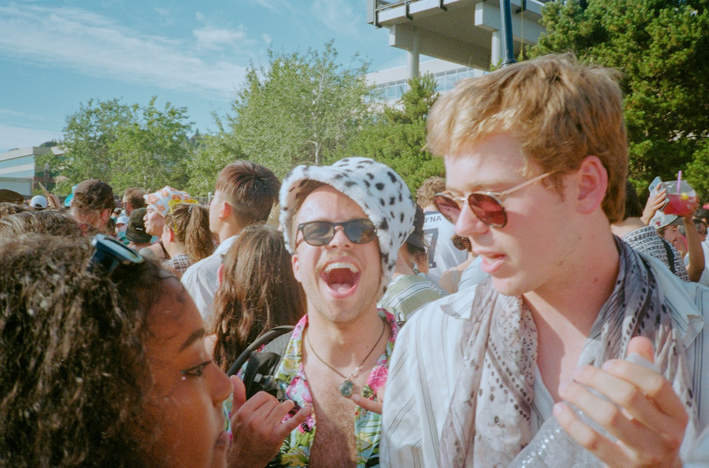 Three friends laughing together at an outdoor public event.