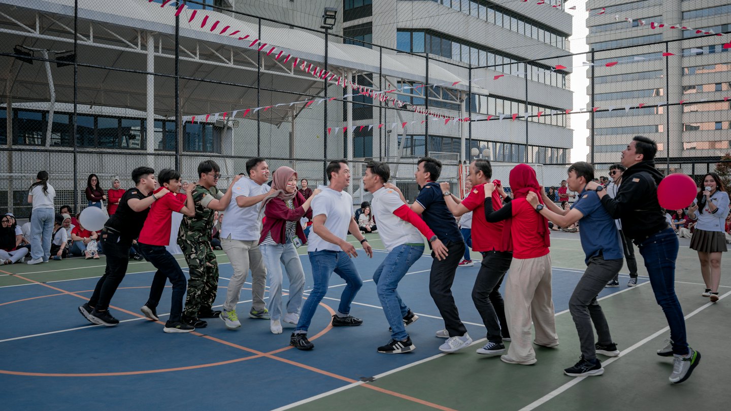 People compete in a team building game on an outdoor court.