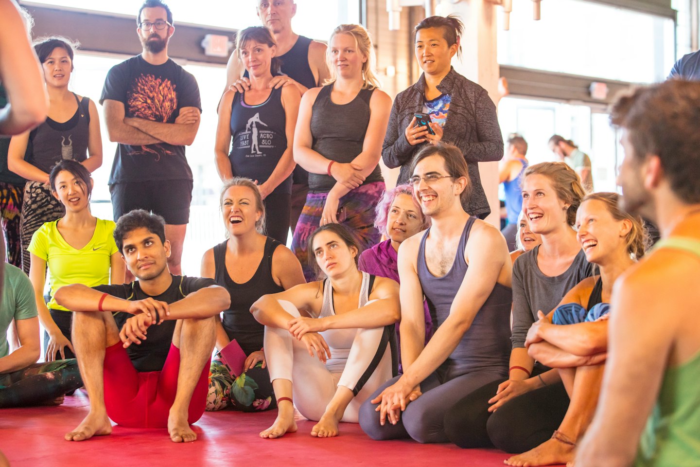 Diverse group of adults smiling during a workshop on a red mat.